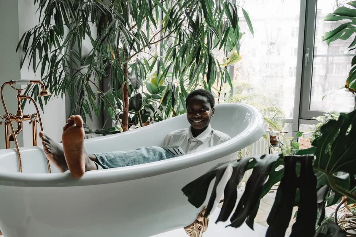 Bol en bois rempli de feuilles de moringa séchées et d'écorces, posé sur le bord d'une baignoire avec des bougies et un tissu wax coloré