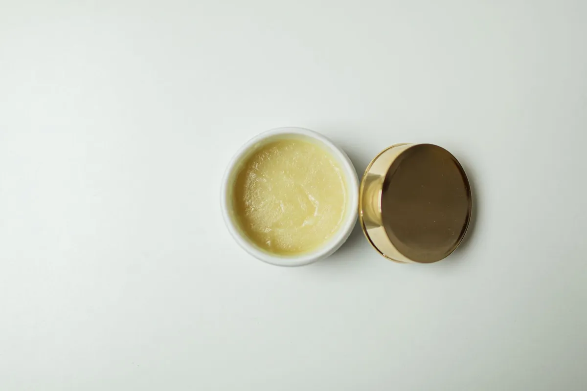 Pot de beurre de karité brut africain sur fond beige