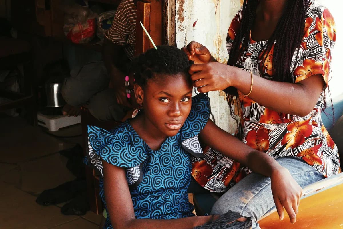Coiffeuse afro professionnelle réalisant des tresses box braids sur une cliente dans un salon parisien lumineux