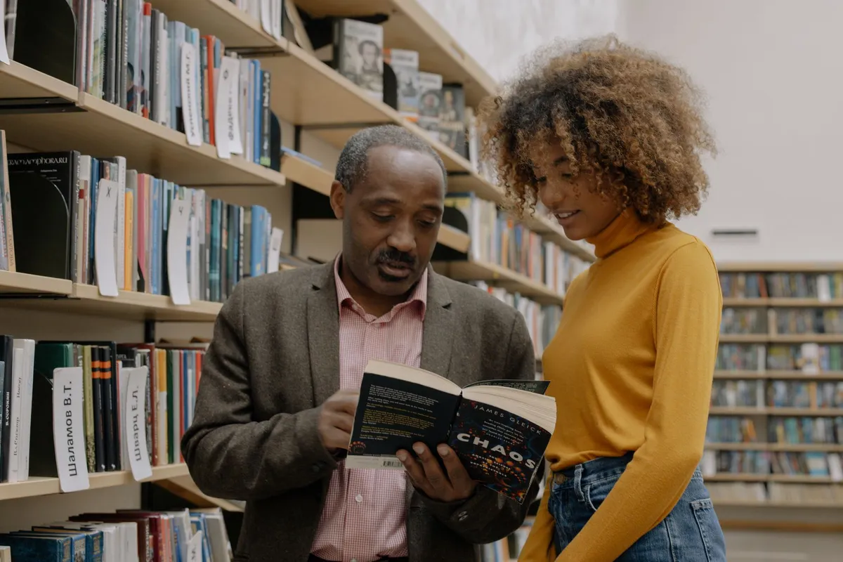 Groupe d'amis souriants lisant des livres afro dans un café parisien lumineux