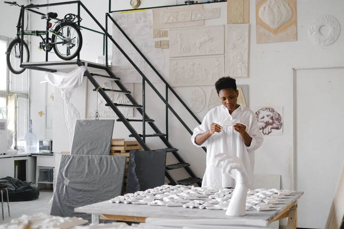 Vase en céramique artisanale et coussin en textile wax disposés sur une console en bois dans un appartement parisien lumineux