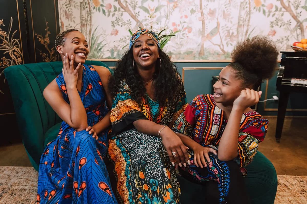 Femme africaine souriante avec des écouteurs sans fil, lumière dorée du matin dans un appartement parisien