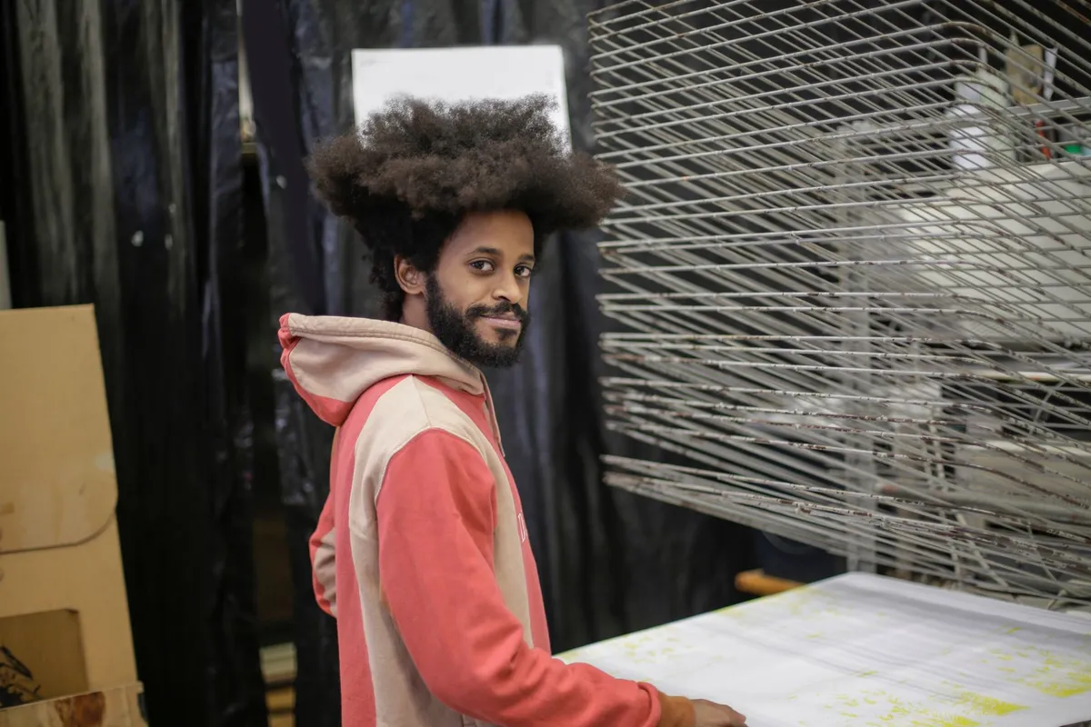 Sérigraphe afro travaillant un motif textile inspiré des cultures africaines dans son atelier en Île-de-France