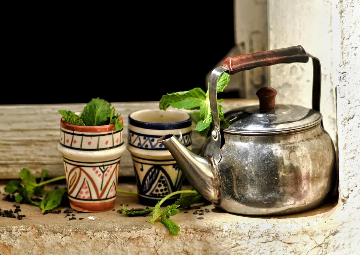 Tasse fumante d'infusion africaine au bissap posée sur une table en bois, entourée de fleurs d'hibiscus séchées et de gingembre frais