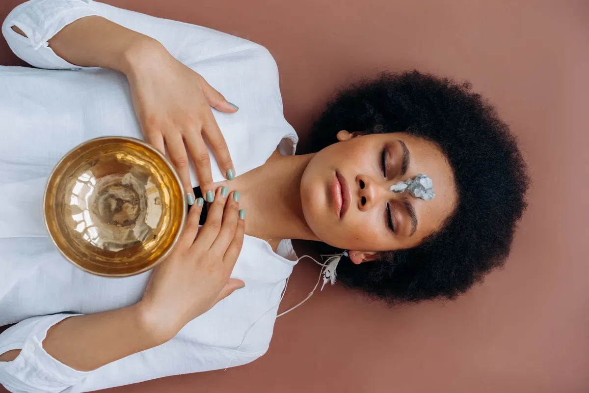 Femme noire en séance de soin naturel à Paris, entourée de plantes tropicales, d'huiles et de bougies, dans une ambiance wellness afro apaisante