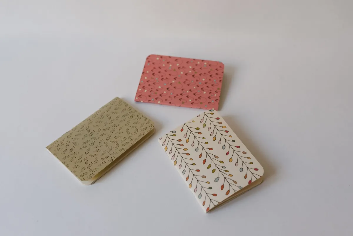 Marque-pages artisanaux colorés et carnet à couverture en tissu wax posés sur une table en bois, ambiance lecture cosy