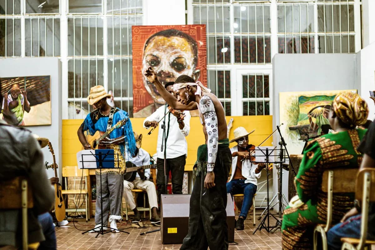 Œuvre d'art africain contemporain exposée dans une galerie parisienne, toiles colorées et sculptures en arrière-plan