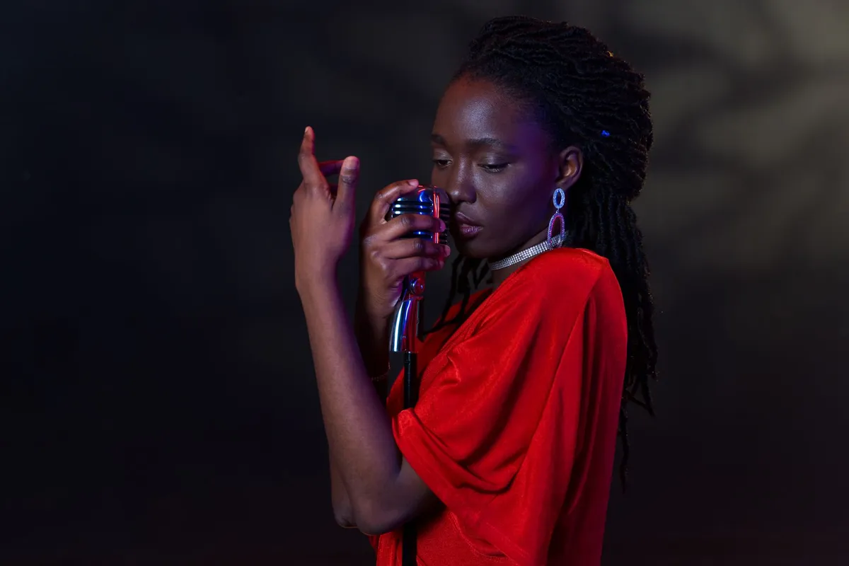 Artiste afro-descendant en studio à Paris, entouré de toiles colorées et d'instruments de musique, lumière dorée
