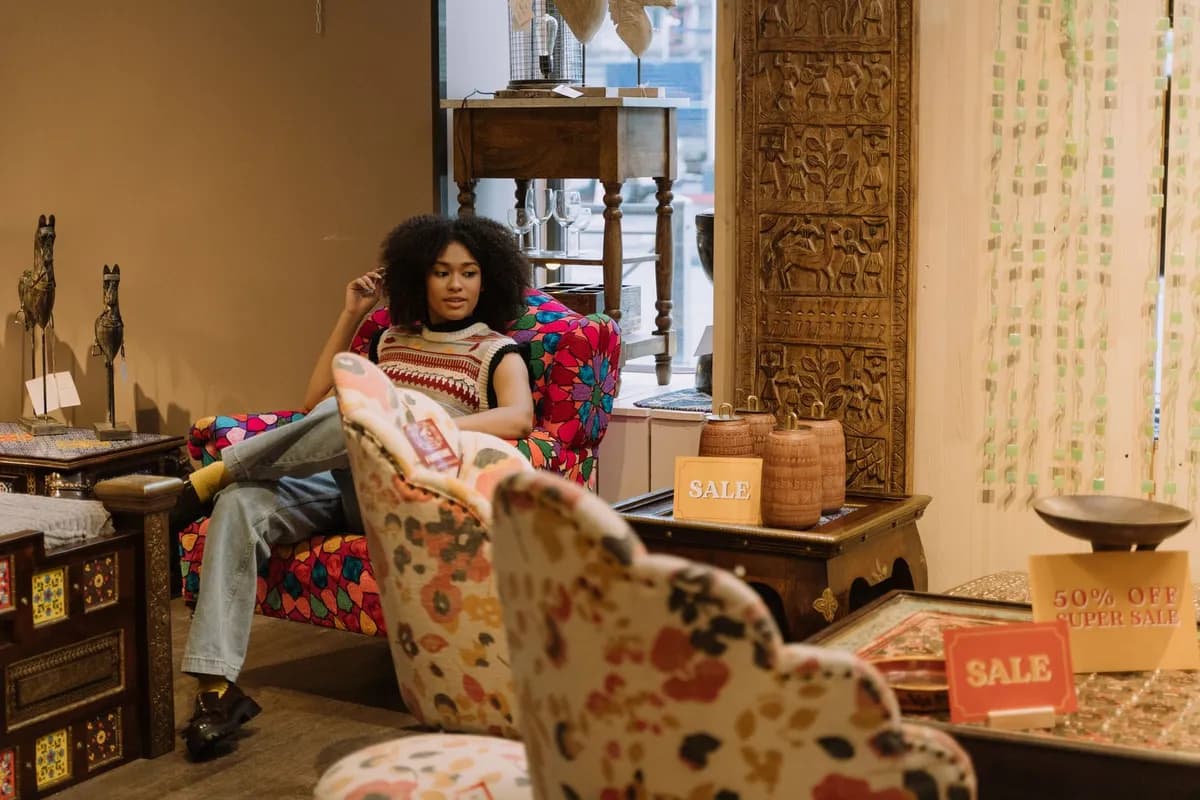 Intérieur lumineux d'un concept store parisien proposant des sculptures en bois, des textiles colorés et du mobilier d'inspiration africaine