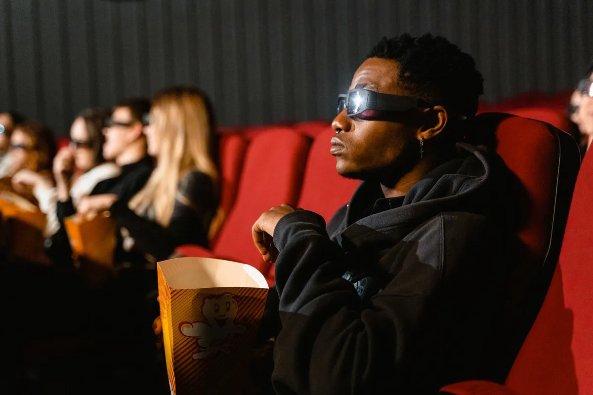 Salle de cinéma parisienne plongée dans la lumière du projecteur, affiche de film africain au mur