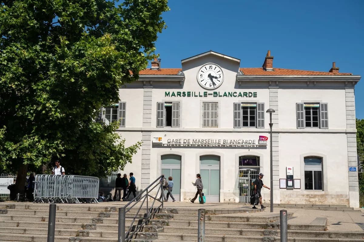 Rue animée de Marseille avec étals de tissus wax et façades colorées au soleil