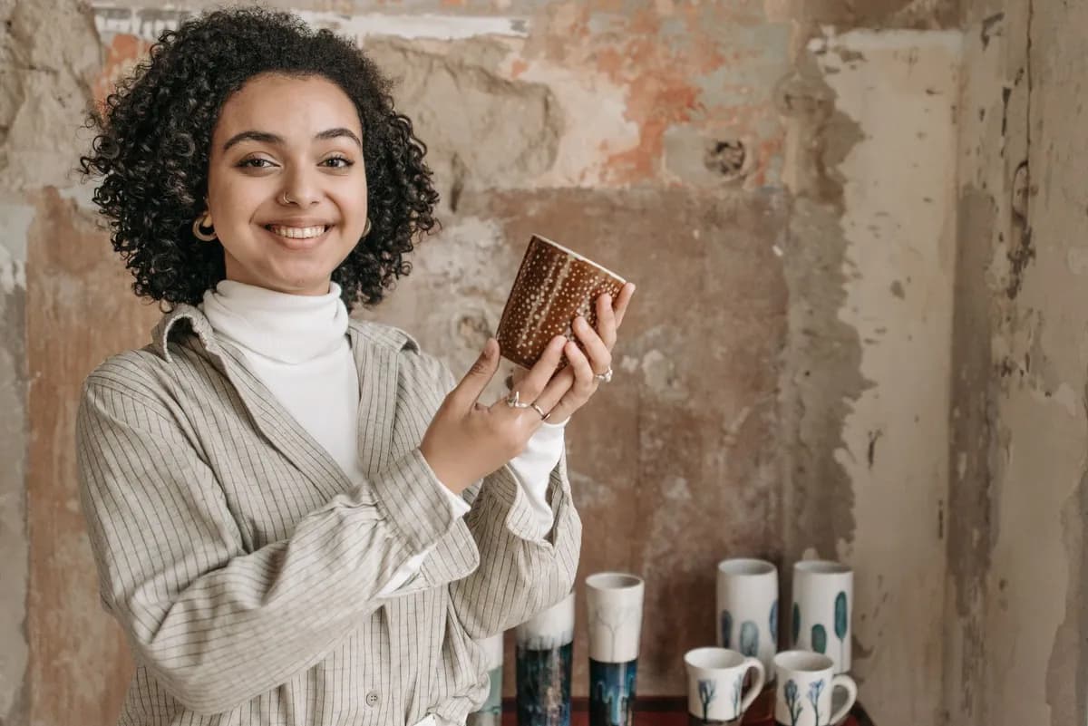 Céramiste afro en train de tourner un vase dans son atelier parisien, entouré d'outils et de pièces en cours de séchage.