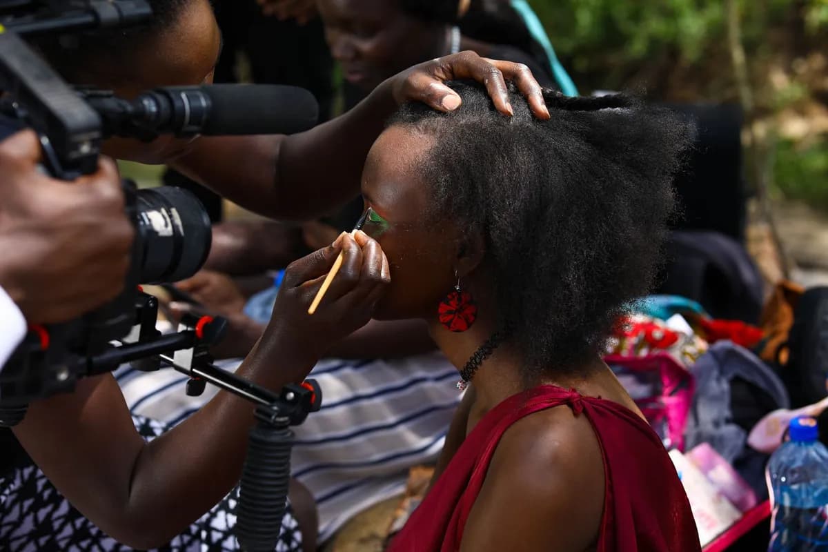 Réalisatrice africaine derrière une caméra sur un tournage, lumière chaude et regard déterminé