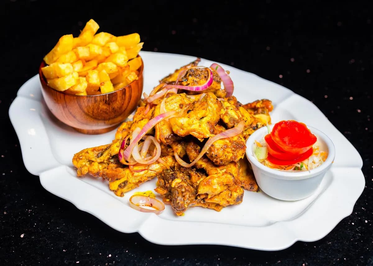 Assiette de garba avec attiéké et thon grillé, servie dans un maquis parisien, ambiance chaleureuse et colorée