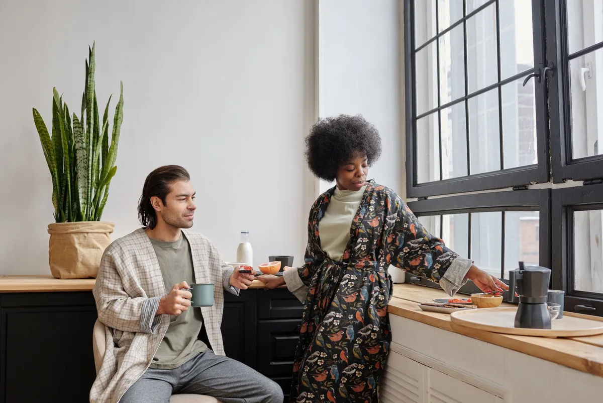 Femme de la diaspora afro souriante préparant son café dans une cuisine parisienne lumineuse, casque sur les oreilles