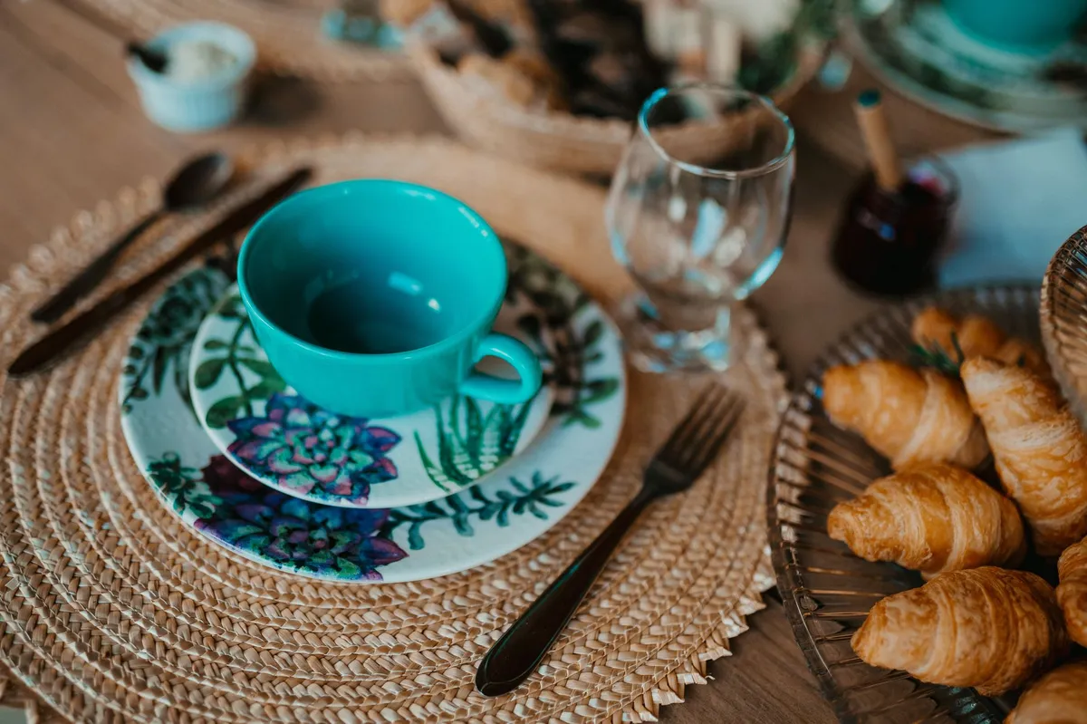 Table dressée à l'africaine avec vaisselle colorée, tissu wax et plats traditionnels au centre