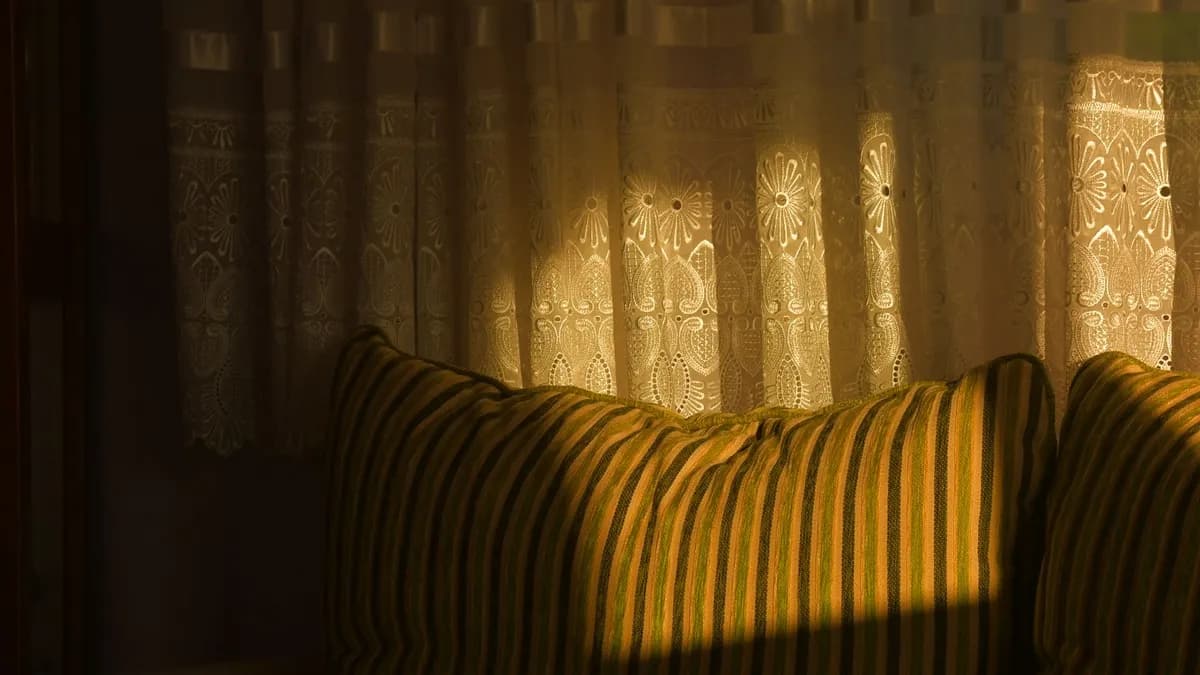 Salon parisien décoré avec des cadres en tissu wax coloré aux motifs géométriques africains, coussins assortis sur un canapé gris