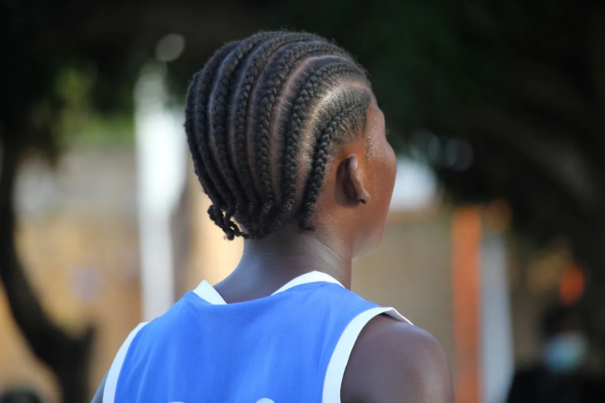 Jeune femme aux box braids longues et soignées dans un salon de coiffure afro à Paris, lumière dorée, ambiance chaleureuse
